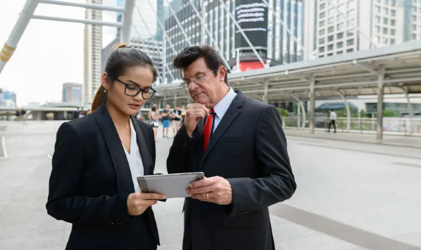 Portrait of mature businessman and young asian businesswoman together as team diversity concept in the city outdoors