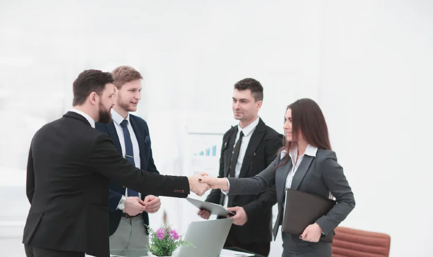 Business woman and businessman handshake while people around